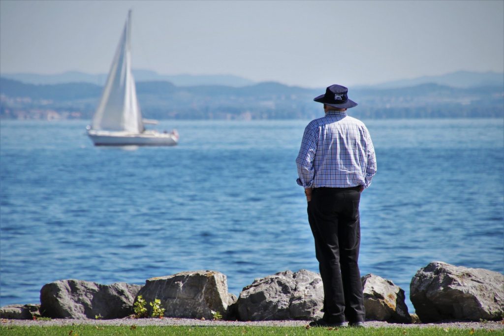 Man looking back at a sail boat on the water